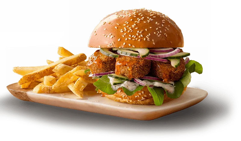 Falafel patty in a sesame bun with fresh veggies with crispy fries