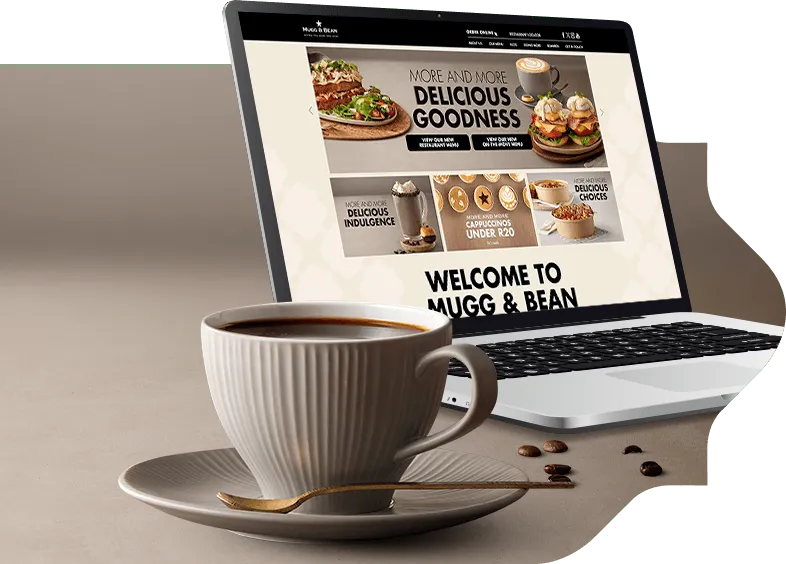  A cup of coffee on a side plate alongside a laptop computer
