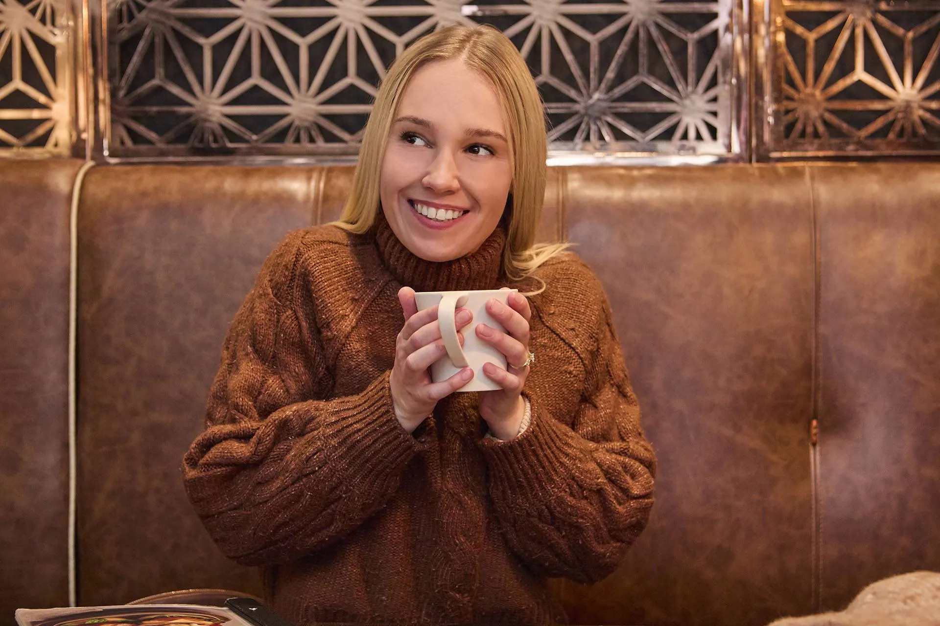 A lady sitting in and enjoying a warm coffee