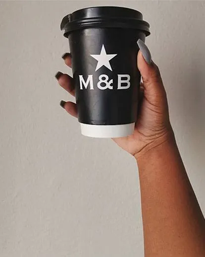 Person holding M&B Takeaway coffee cup