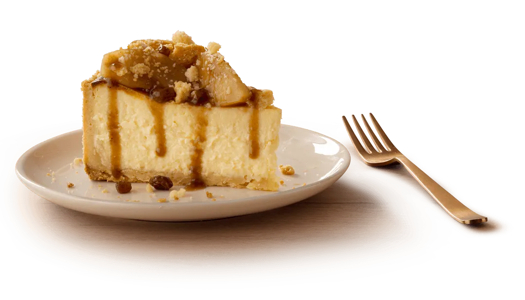 A slice of apple pie cheesecake with a crumbly base and caramel drizzle